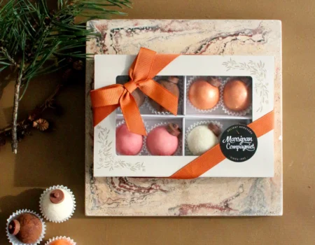Søt liten eske for søt konfekt produsert av Moltzau Packaging for Marsipan Compagniets håndverkskonditori. Her med deres julekuler, pyntet med klistremerke og oransje bånd.